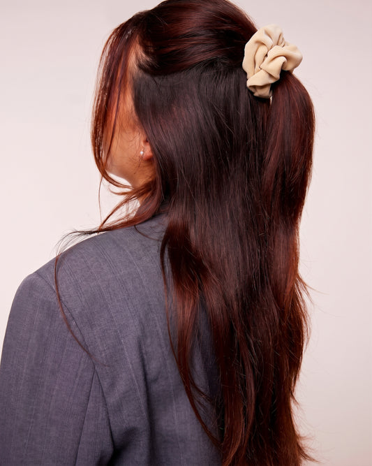 Petit chouchou en velours beige porté dans les cheveux